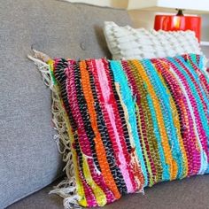 a multicolored pillow sitting on top of a gray couch