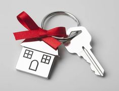 a house shaped keychain with a red ribbon tied around it's edge