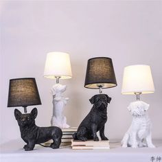 three black and white dog figurines sitting next to lamps