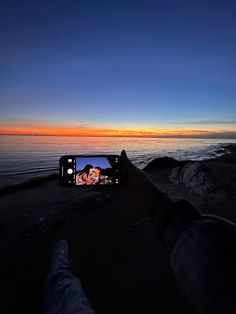 someone taking a photo with their cell phone on the beach at sunset or sunrise time