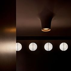 four round windows in a dark room with light coming through the window and on the wall