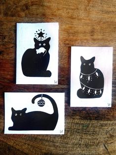 three black cats on white cards sitting on top of a wooden table