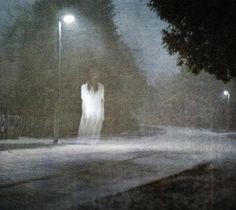 two people are walking down the street in the rain at night with one person holding an umbrella