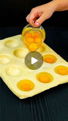 someone is pouring eggs into an egg tray on a black surface with holes in it