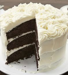 a large chocolate cake with white frosting on a plate