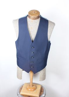 "ALL CLOTHING SALES ARE FINAL. How sharp is this vest, though? Wow. Navy polyester 5-button with perfect fit back. Back has satin coin pattern material. No smoke, mildew or damage. Please check measurements before purchasing. Measurements:  Chest: 34\" Length: 23\" Pair with many of the handsome ties available in the shop right now and save on shipping! I'm here to make you look good. What a fun item! Thank you for looking!" Blue Sleeveless Outerwear With Buttons, Formal Sleeveless Vest With Button Closure, Classic Tailored Vest With Button Closure, Tailored Sleeveless Vest With Button Closure, Fitted Vest With Snap Buttons For Work, Classic Single-breasted Sleeveless Vest, Classic Tailored Vest With Buttons, Formal Blue Vest With Buttons, Fitted Blue Denim Vest With Snap Buttons