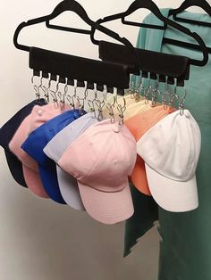 several hats are hanging on a rack with hooks attached to the hat hanger, which also holds baseball caps