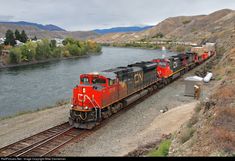 a train traveling down tracks next to a river