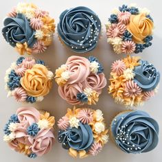 cupcakes decorated with blue, yellow and pink frosting are arranged on a white surface