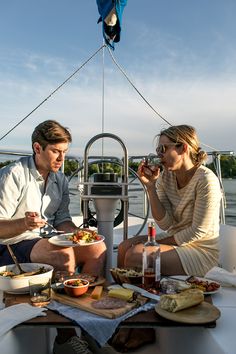 a man and woman sitting on a boat eating food from the bowl in front of them