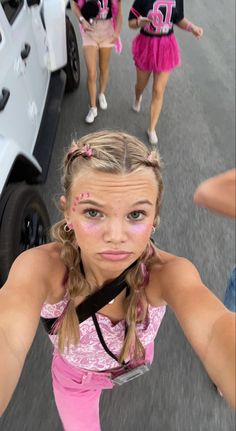 two girls in pink dresses are walking down the street with their hands on their hips