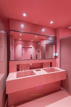 a pink bathroom with two sinks and mirrors