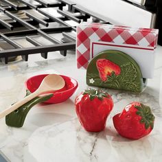 three red strawberries sitting on top of a counter next to a bowl and spoon