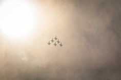 four fighter jets flying in formation against the sun