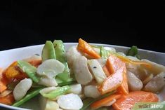 a white bowl filled with carrots, scallops and cashews on top of a table