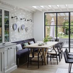 a dining room with white brick walls and black chairs