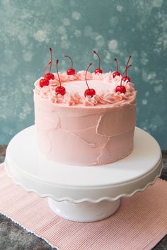 a cake with pink frosting and cherries on top