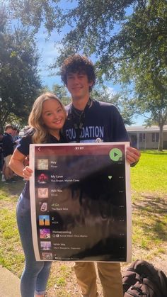 a man and woman standing next to each other holding up a sign