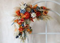 an arrangement of flowers and feathers on a white arch in front of a wall with a window