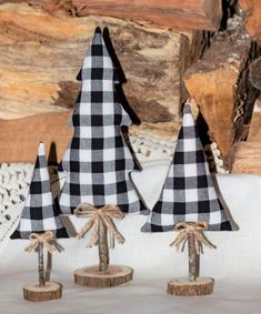 three small black and white christmas trees on wooden bases with burlocks tied around them