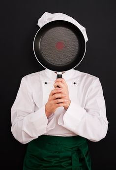 a chef holding a frying pan on his head