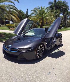 the bmw i8 is parked in front of some palm trees