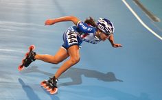 a female rollerblader in action on an indoor track with blue and white paint