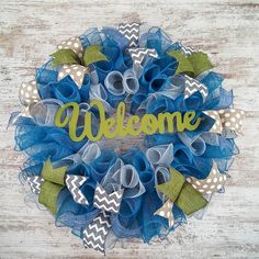 a blue and white wreath with the word welcome on it, sitting on a wooden surface