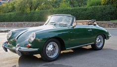 an old green sports car parked in a parking lot