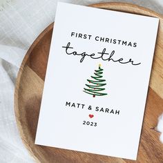 the first christmas together card is on a wooden plate