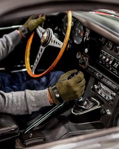 a man sitting in the driver's seat of a car with his hands on the steering wheel