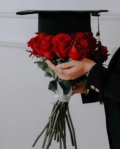 a person in a graduation cap holding red roses