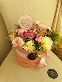 a pink flower box with flowers in it sitting on a chair next to a heart shaped sign