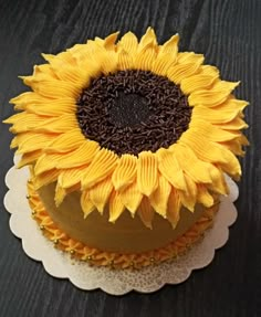 a sunflower cake with chocolate frosting and sprinkles sits on a doily