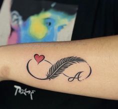 a woman's arm with a feather and a heart tattoo on the left forearm