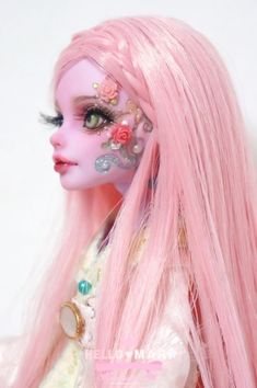 a doll with long pink hair and flowers on it's face is posed in front of a white background