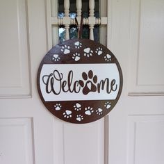 a welcome sign hanging from the front door of a house with paw prints on it