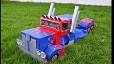 a toy truck made out of cardboard sitting in the grass with two poles sticking out of it's side