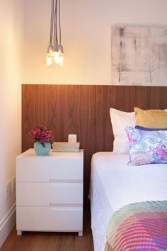 a white bed sitting next to a night stand with two lamps on top of it