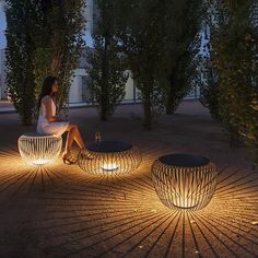 a woman sitting on top of a chair next to two tables with lights around them