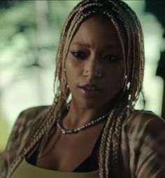 a woman with dreadlocks is looking at the camera while wearing a yellow top