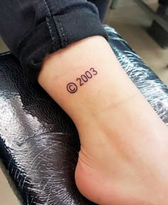 a person with a small tattoo on their foot that reads 2013 and has the date in it