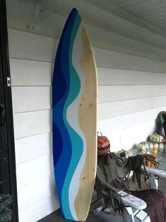 a surfboard leaning up against a wall next to a chair and other items on the ground