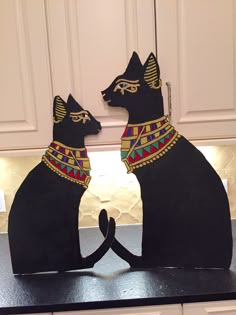 two black cats sitting on top of a counter