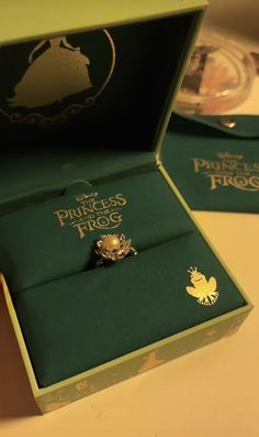 an open box with a ring in it sitting on a table next to other boxes