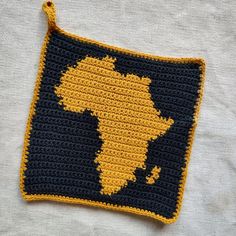 a crocheted africa map is shown on a white surface with black and yellow accents