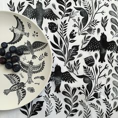 a white plate with black birds and leaves on it next to a wallpaper pattern