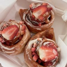 three pastries with strawberries and icing in a box