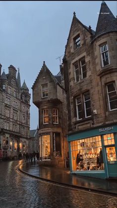 an old european city street at dusk with people walking on the sidewalk and buildings in the background