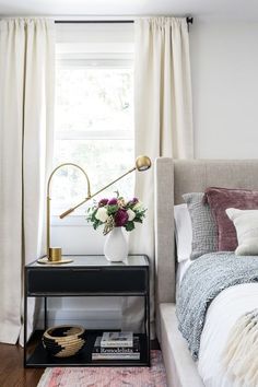 a bed room with a neatly made bed and a vase filled with flowers on the nightstand